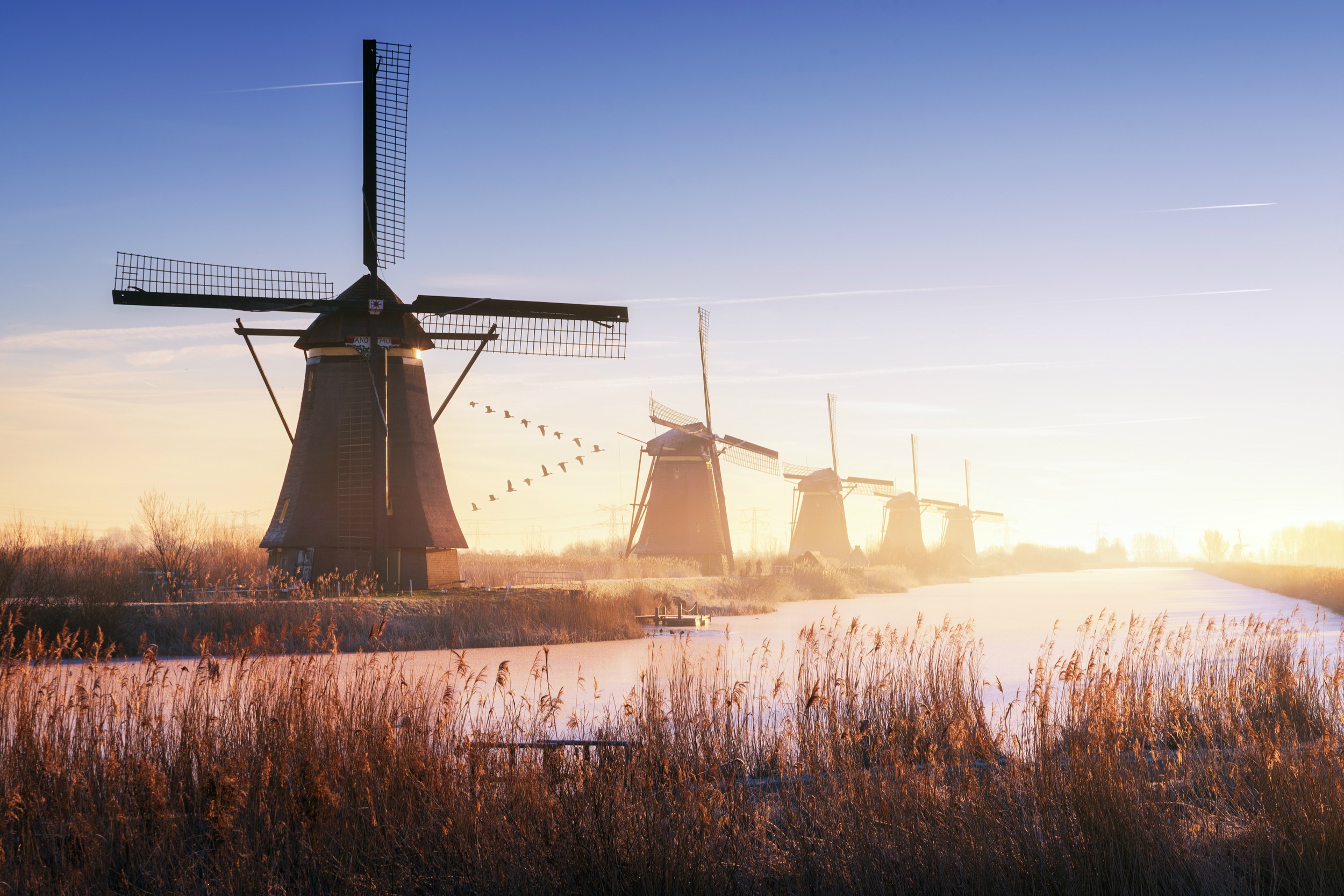 Download mobile wallpaper Building, Sunrise, River, Windmill, Man Made for free.