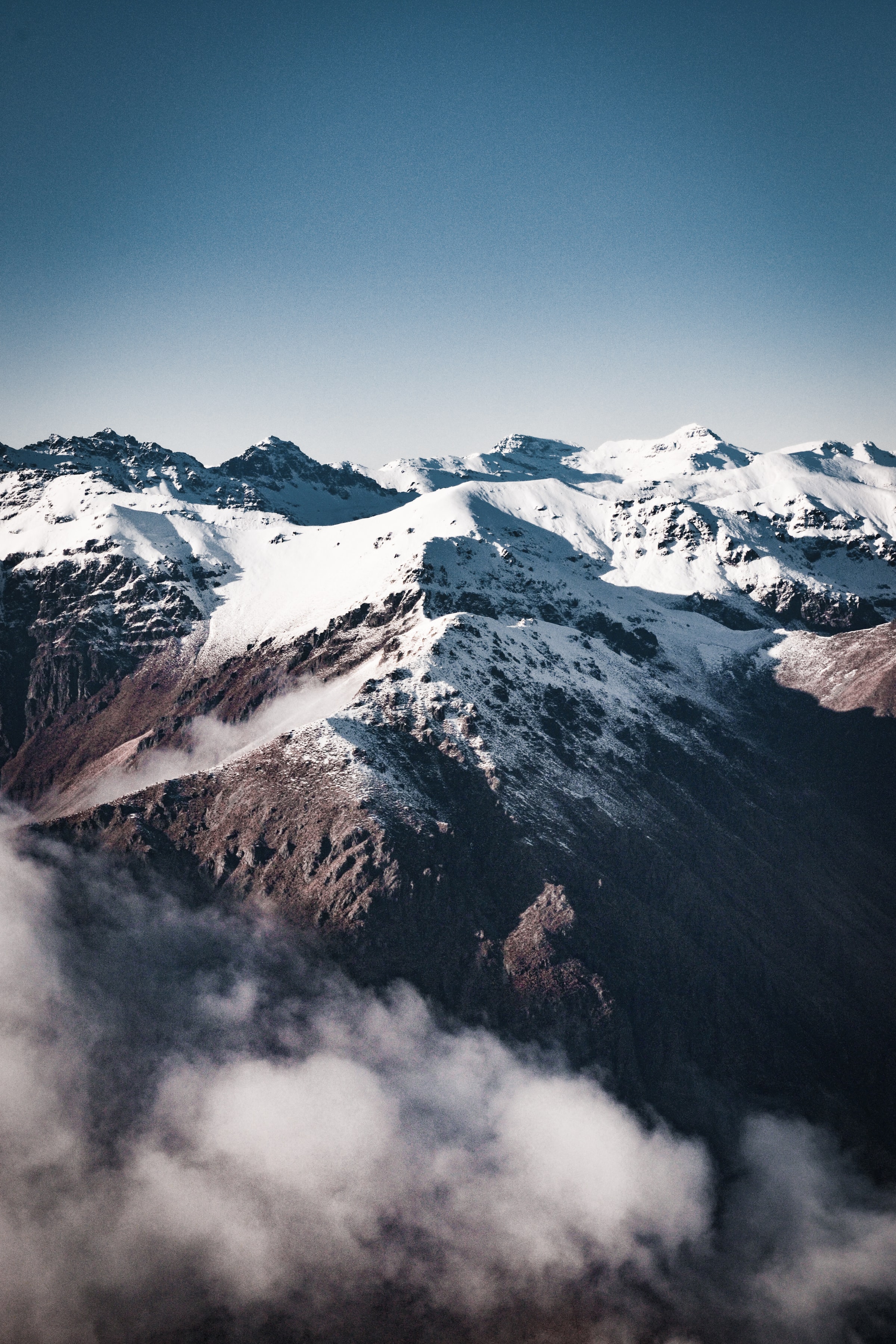 Скачать картинку Скалы, Туман, Заснеженный, Снег, Горы, Природа в телефон бесплатно.