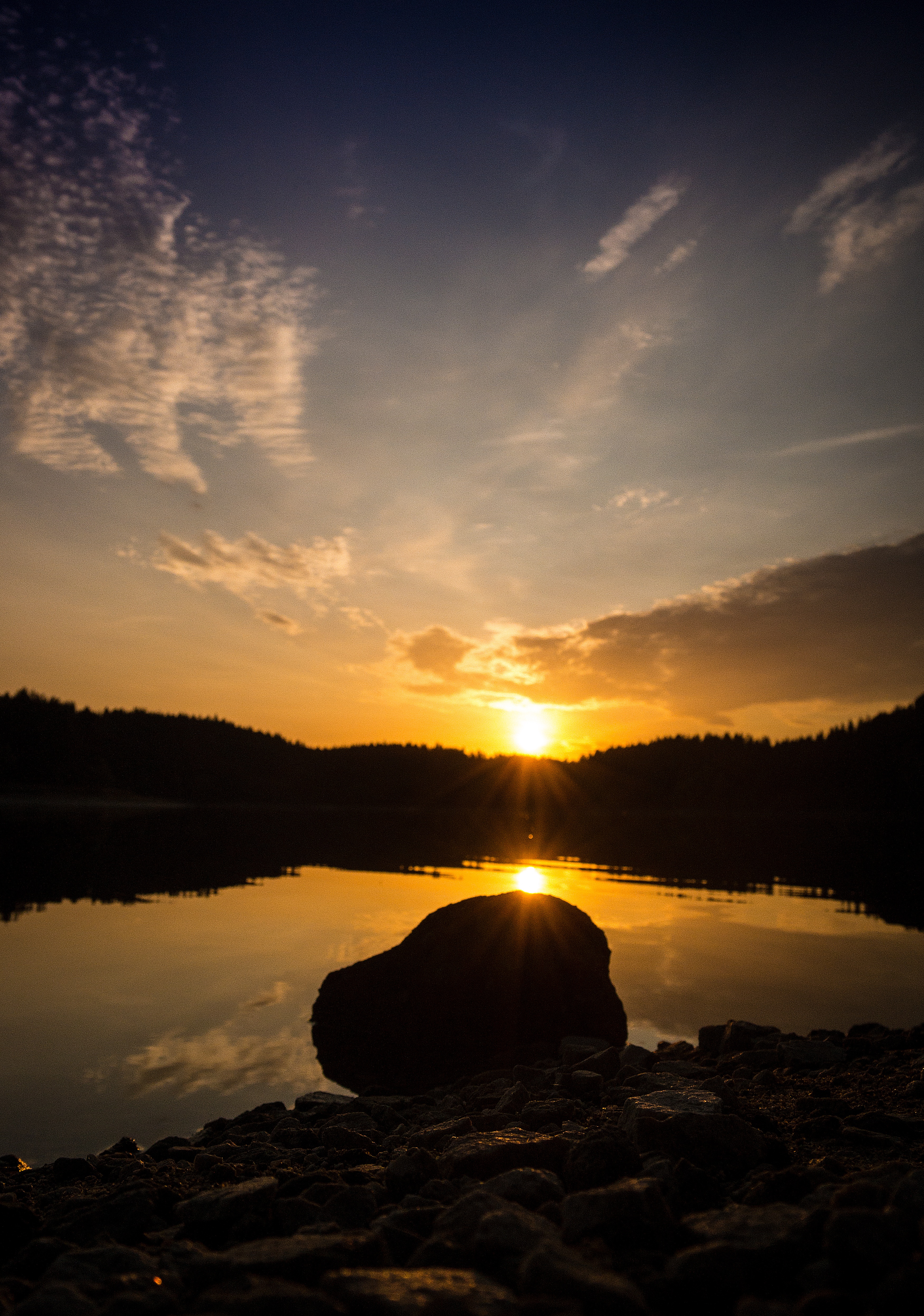 Download background stone, nature, sunset, sky, sun, rock, lake, reflection, shore, bank, forest