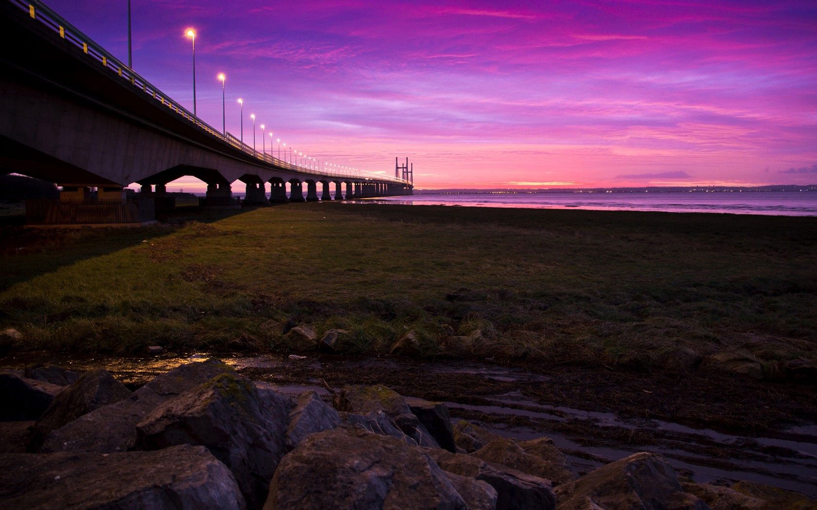 Download mobile wallpaper Bridge, Cities, Rivers, Sky, Lights, Road, Sunset for free.