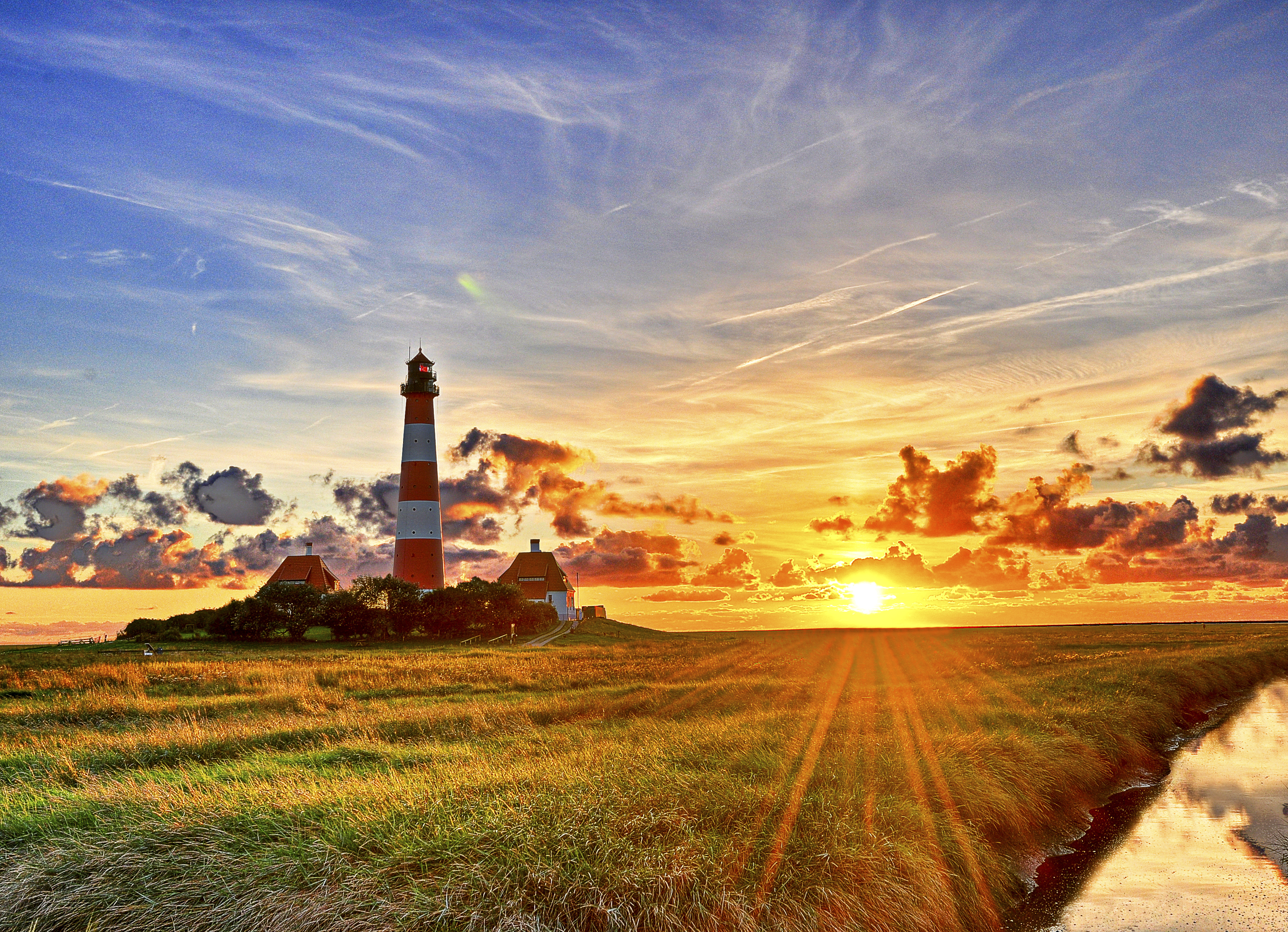 Download mobile wallpaper Sunset, Sky, Horizon, Lighthouse, Sunbeam, Man Made for free.