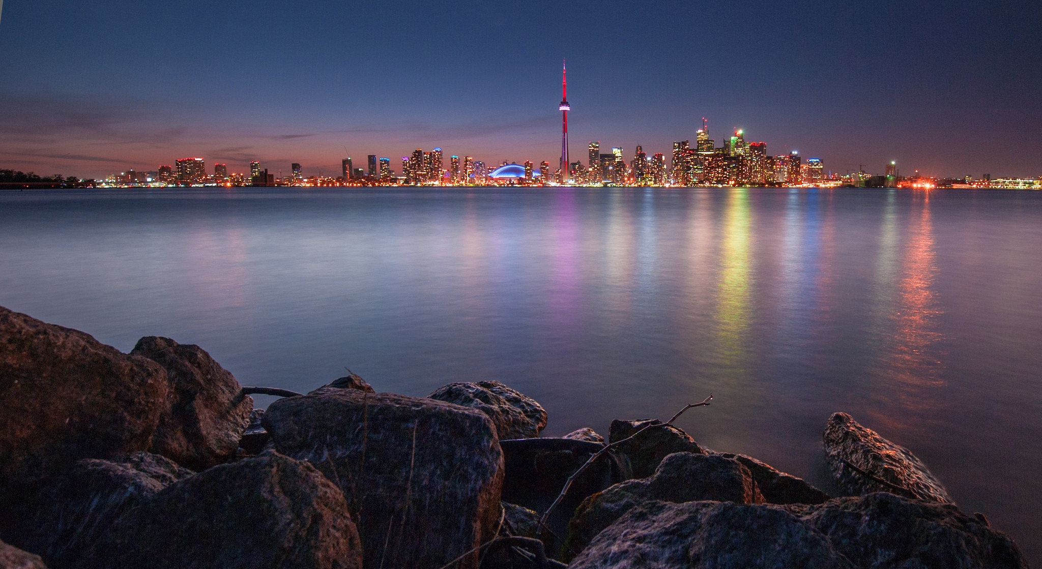 Скачать картинку Торонто, Отражение, Огни, Камни, Города, Ночь, Озеро, Город, Канада в телефон бесплатно.