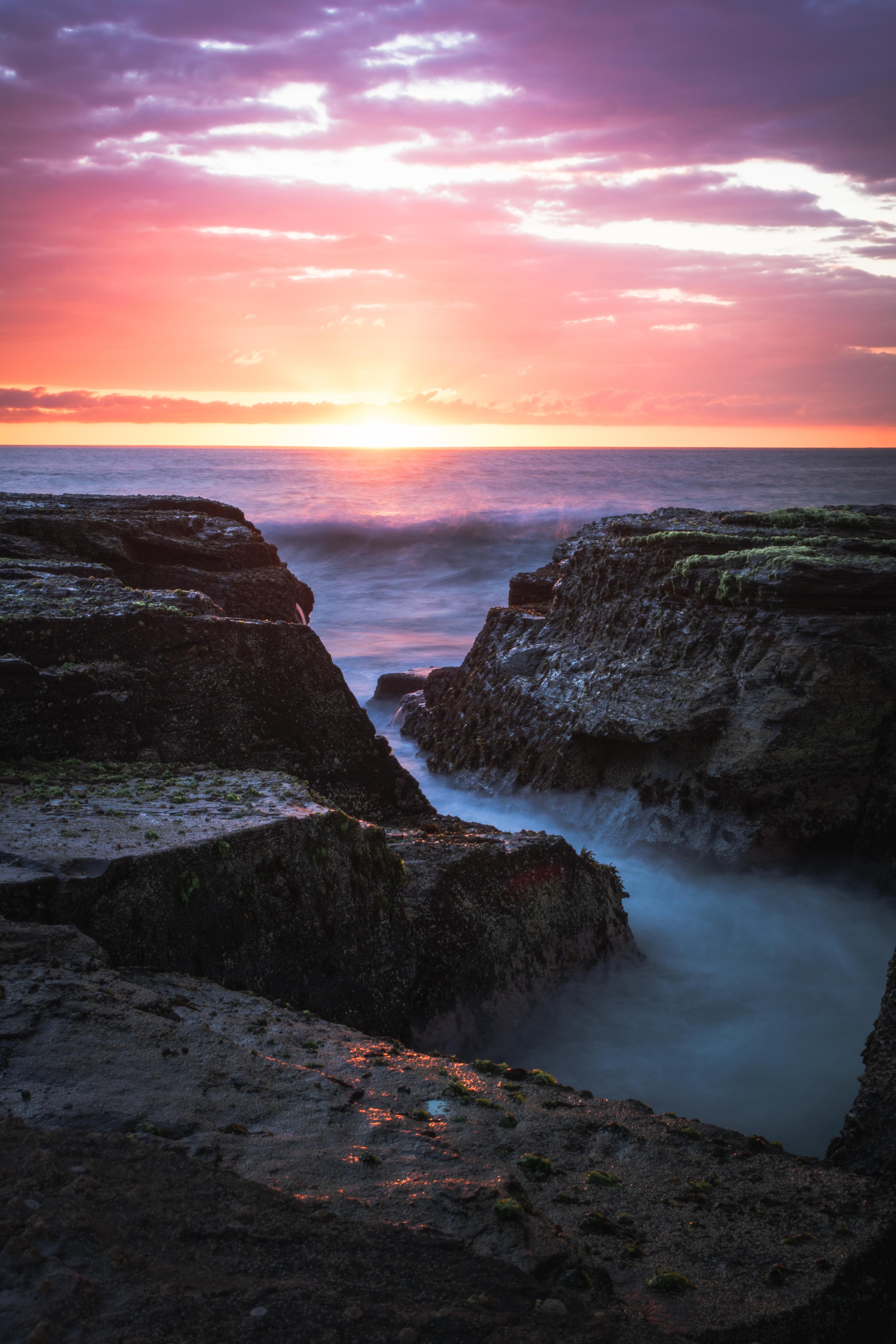 Download mobile wallpaper Rocks, Sea, Sunset, Waves, Horizon, Nature for free.