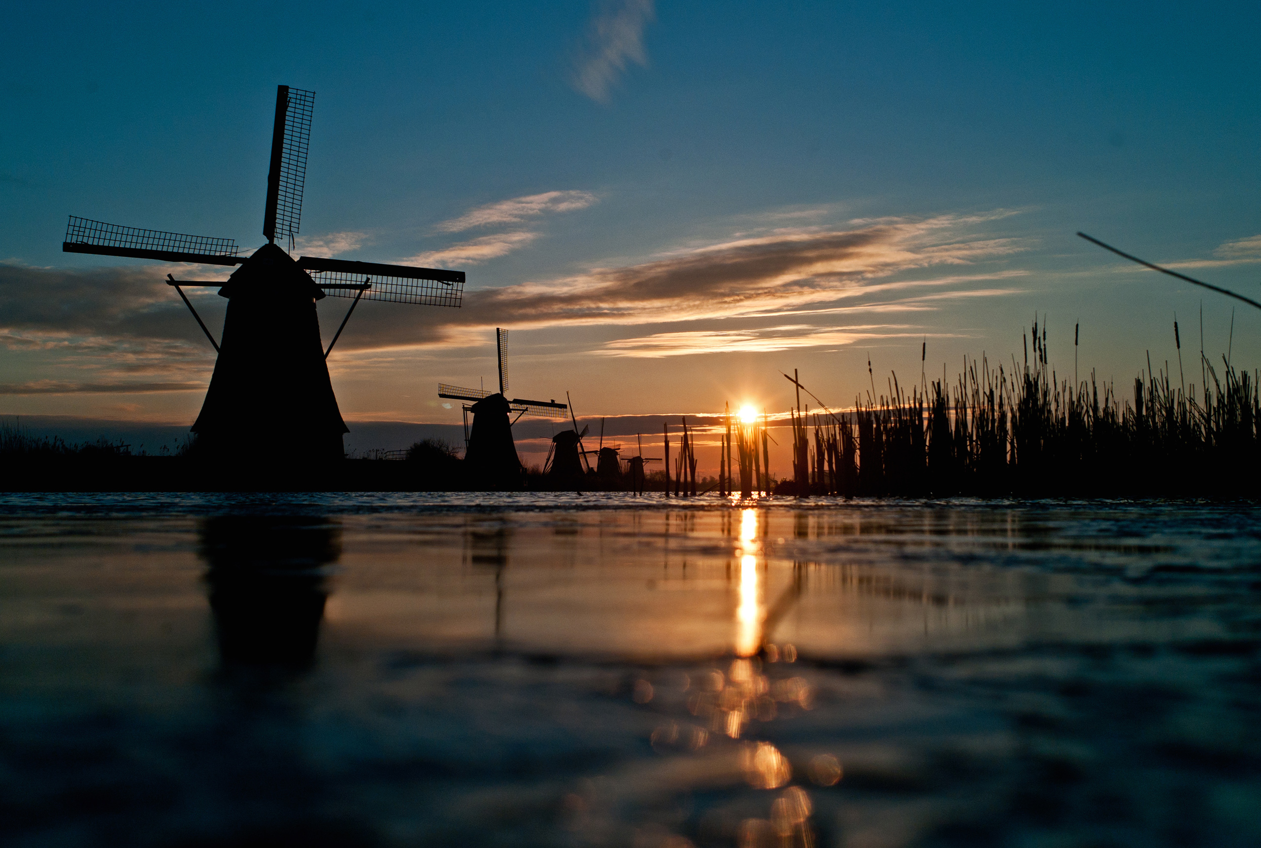 Download mobile wallpaper Water, Sunset, Grass, Sky, Reflection, Cloud, Windmill, Man Made for free.