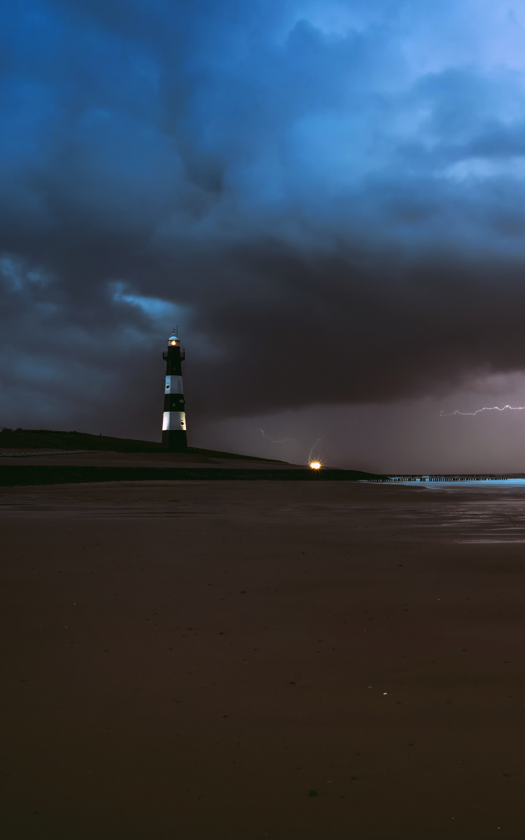 Download mobile wallpaper Night, Beach, Sand, Lightning, Lighthouse, Man Made for free.