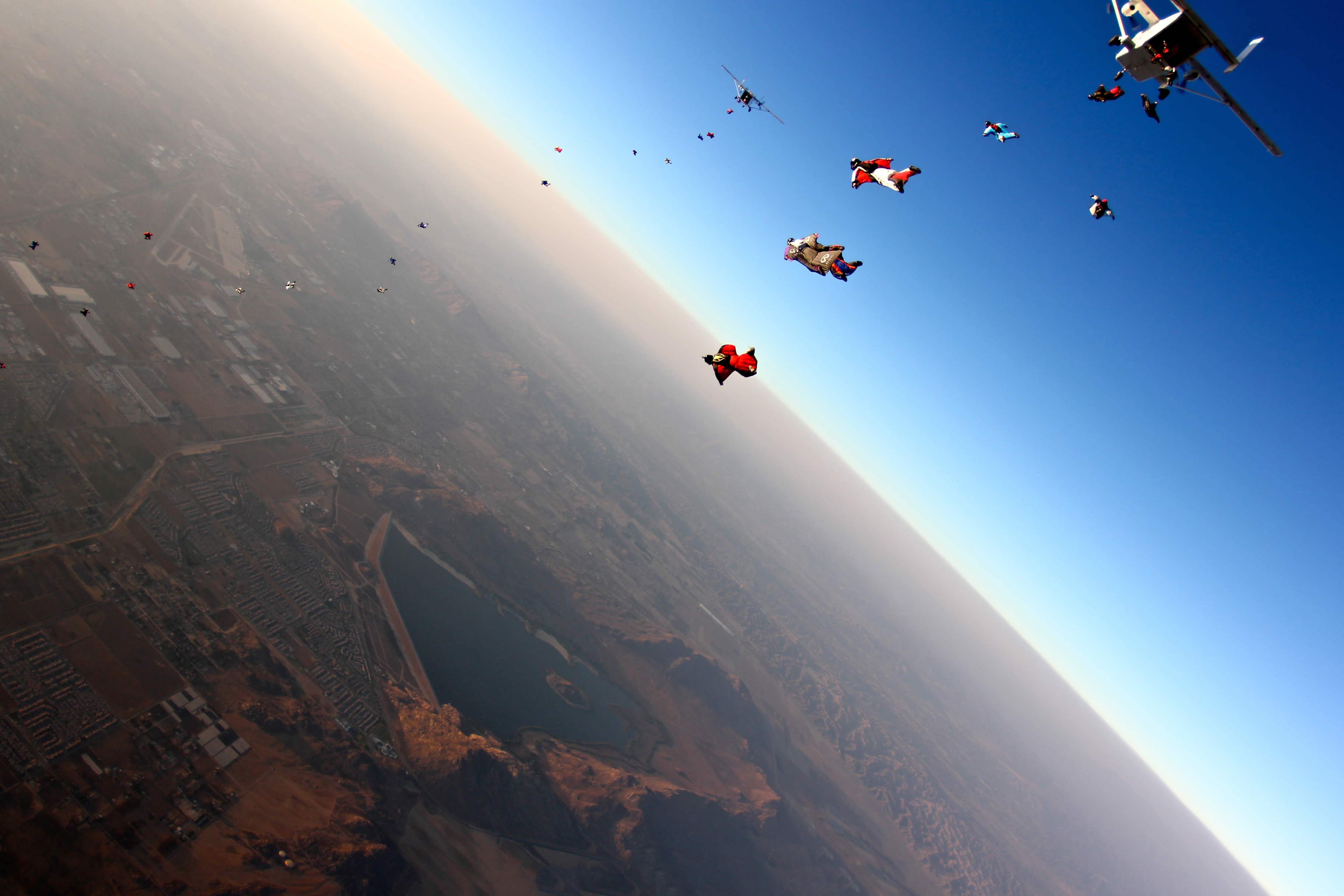 144116 скачать обои парашютисты, прыжок, полет, спорт, город, самолет - заставки и картинки бесплатно