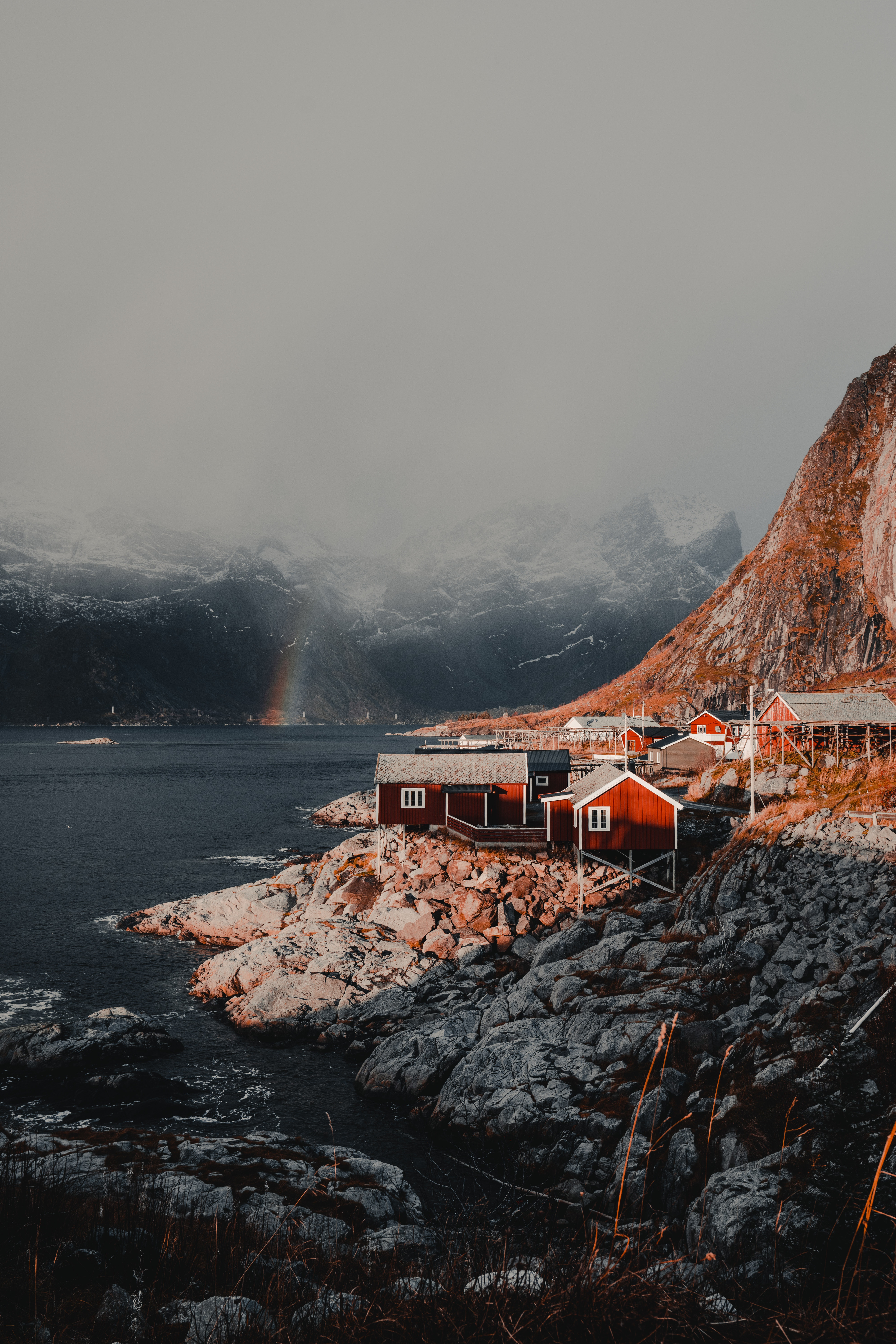 146496 скачать картинку норвегия, домики, горы, природа, радуга, туман, лофотенские острова - обои и заставки бесплатно