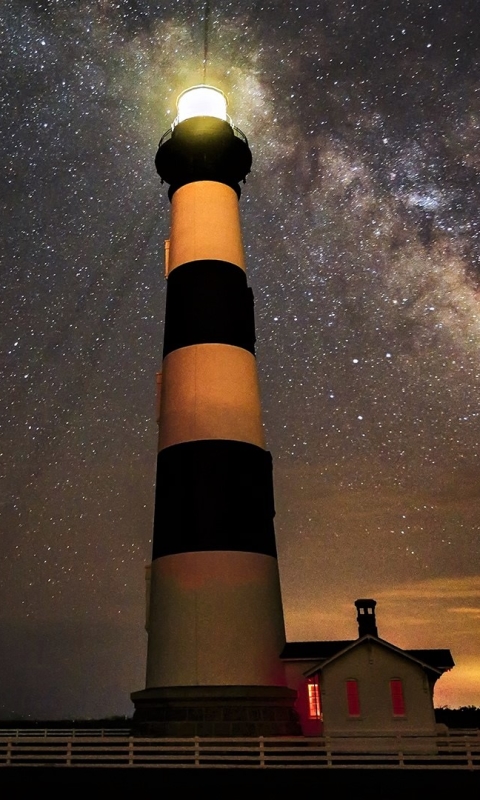 Download mobile wallpaper Sky, Stars, Night, Light, Starry Sky, Milky Way, Lighthouse, Man Made, Bodie Island Lighthouse for free.