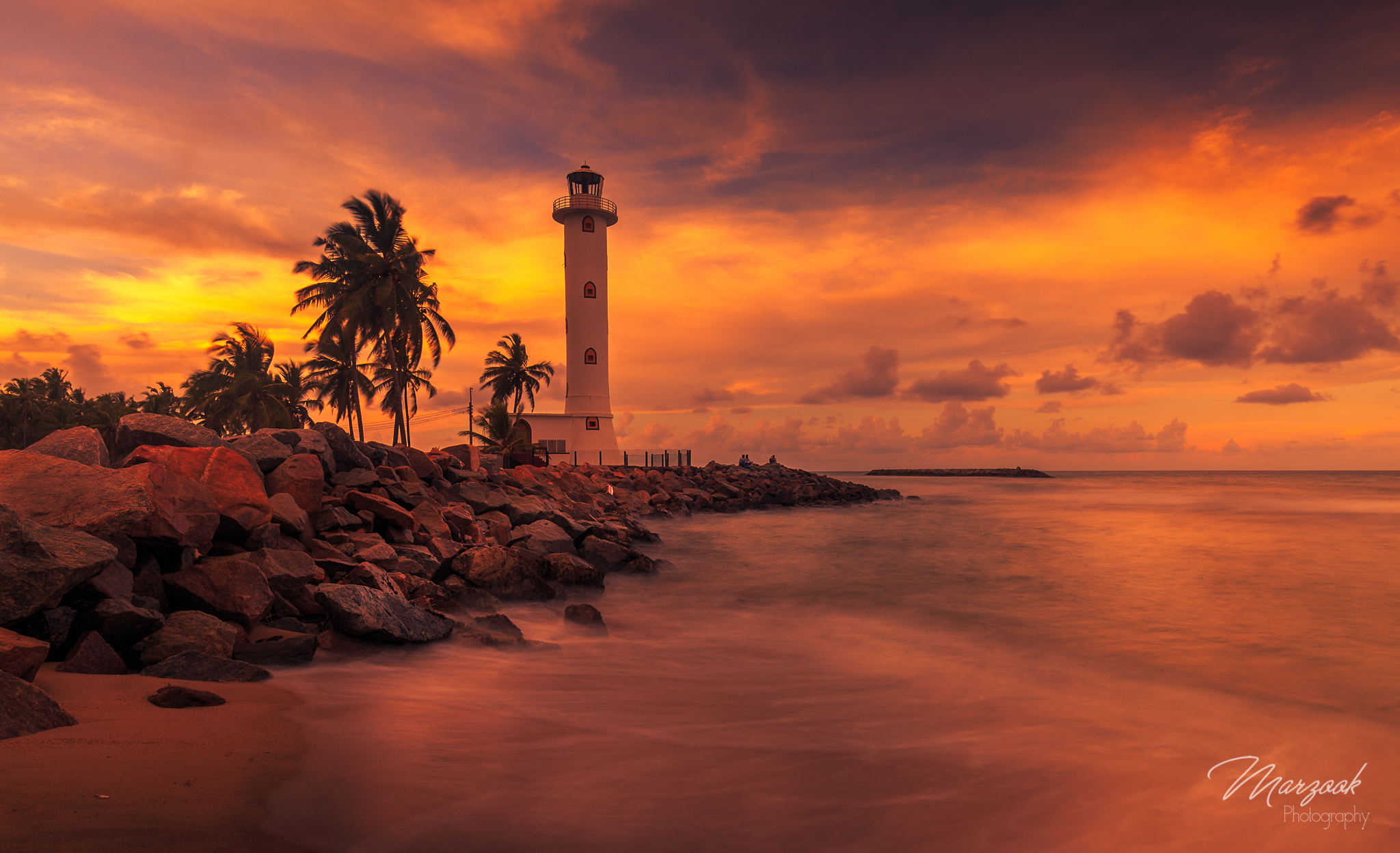 Download mobile wallpaper Sunset, Sea, Horizon, Ocean, Lighthouse, Tropical, Man Made, Palm Tree for free.
