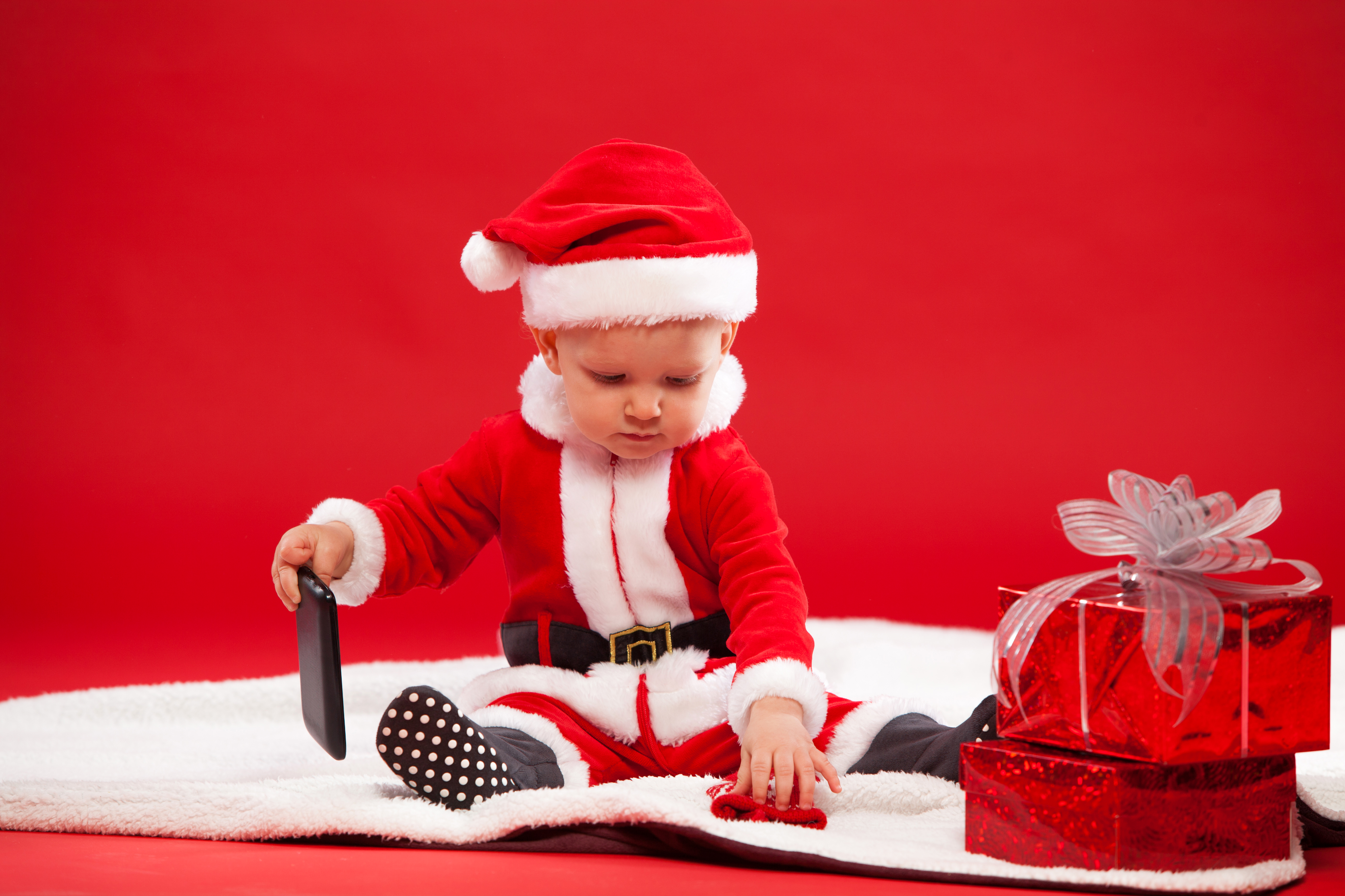 Скачать картинку Красный, Рождество, Малыш, Телефон, Фотографии, Подарки, Шляпа Санты в телефон бесплатно.