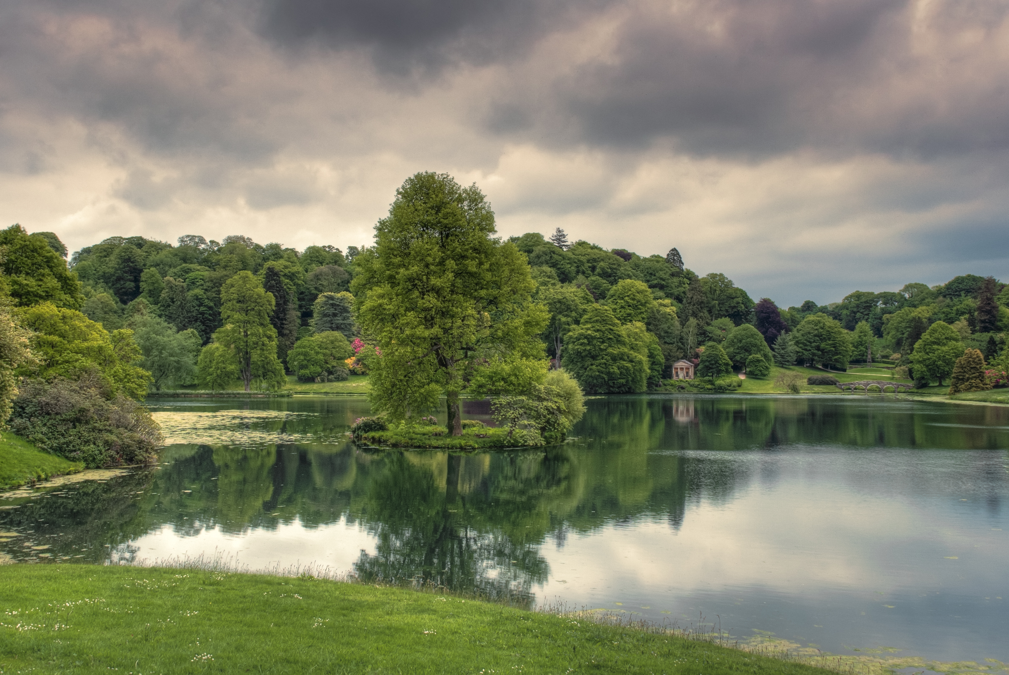 107517 скачать картинку озеро, деревья, природа, трава, отражение, облачно - обои и заставки бесплатно
