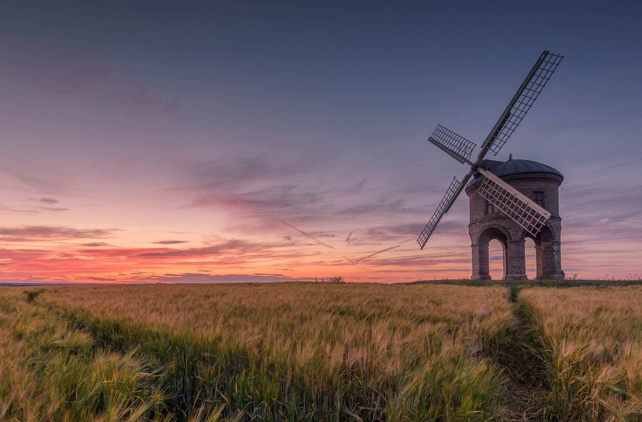 Download mobile wallpaper Sunset, Field, Windmill, England, Man Made for free.