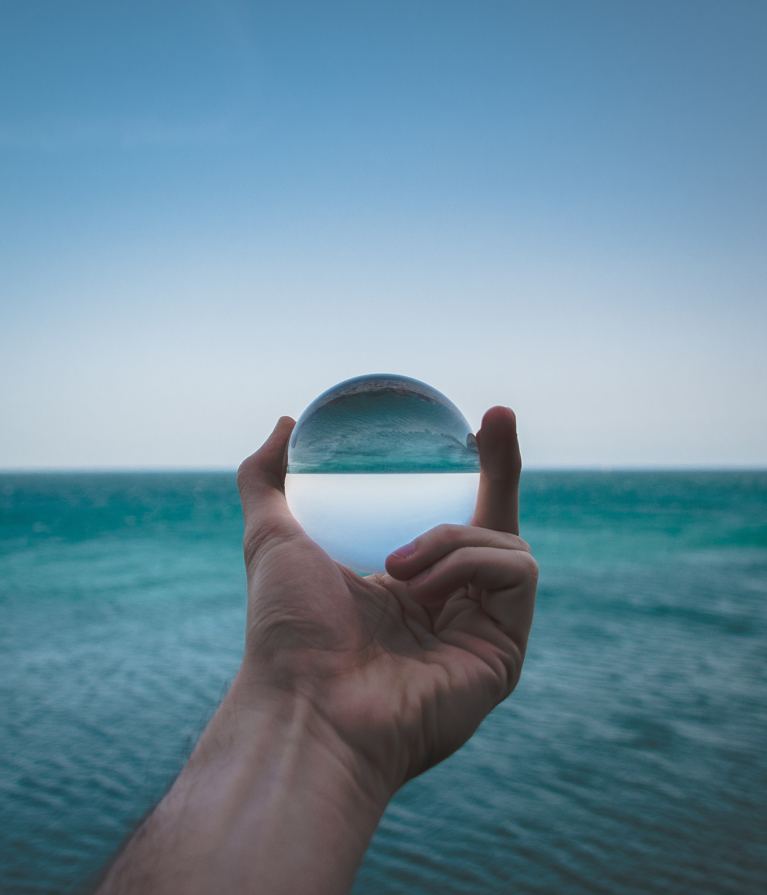 Free download wallpaper Sea, Reflection, Miscellanea, Ball, Distortion, Miscellaneous, Glass, Hand on your PC desktop