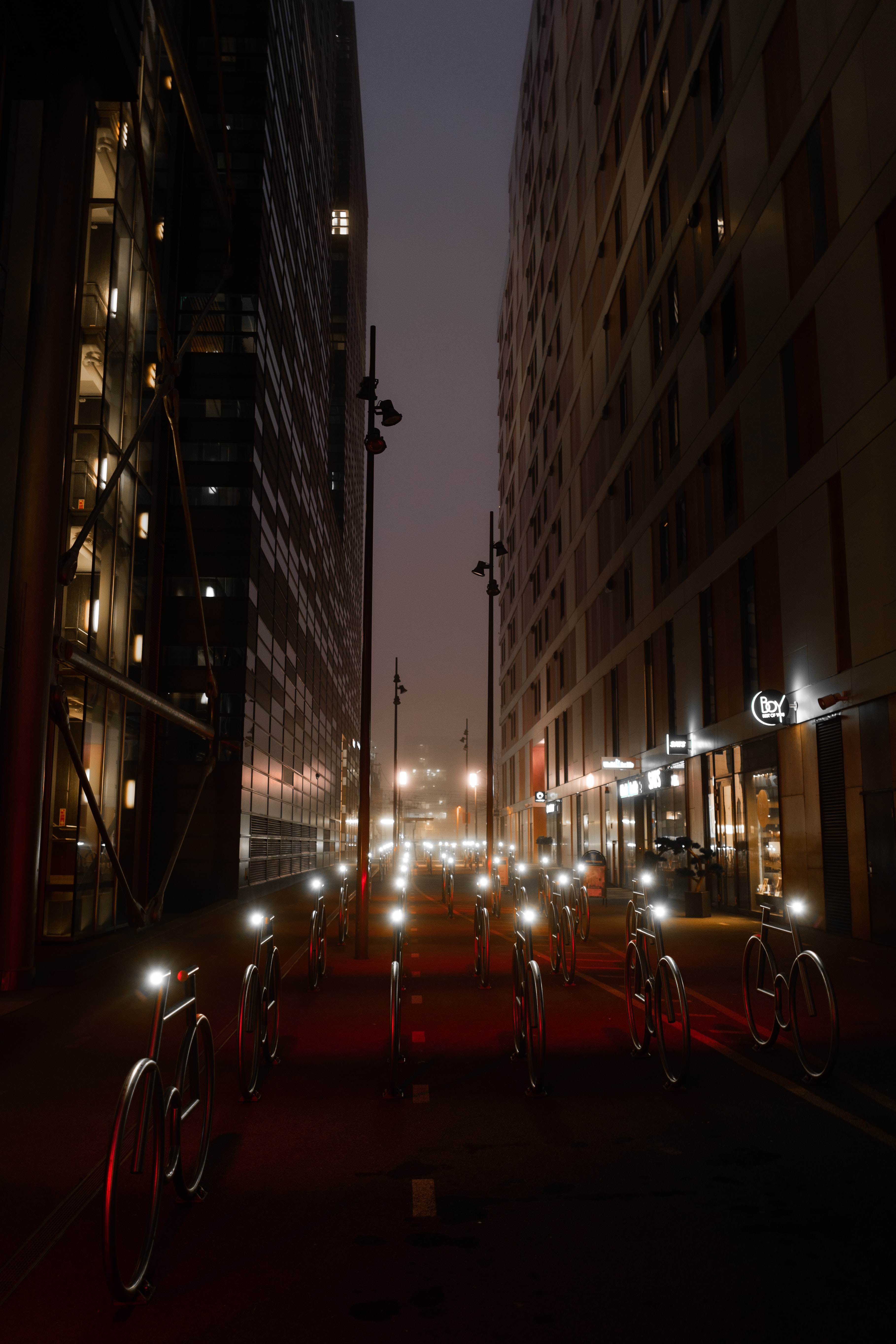 106592 baixar imagens noite, bicicletas, prédio, edifício, as luzes, luzes, escuro, estrada, caminho, projetar, construções - papéis de parede e protetores de tela gratuitamente