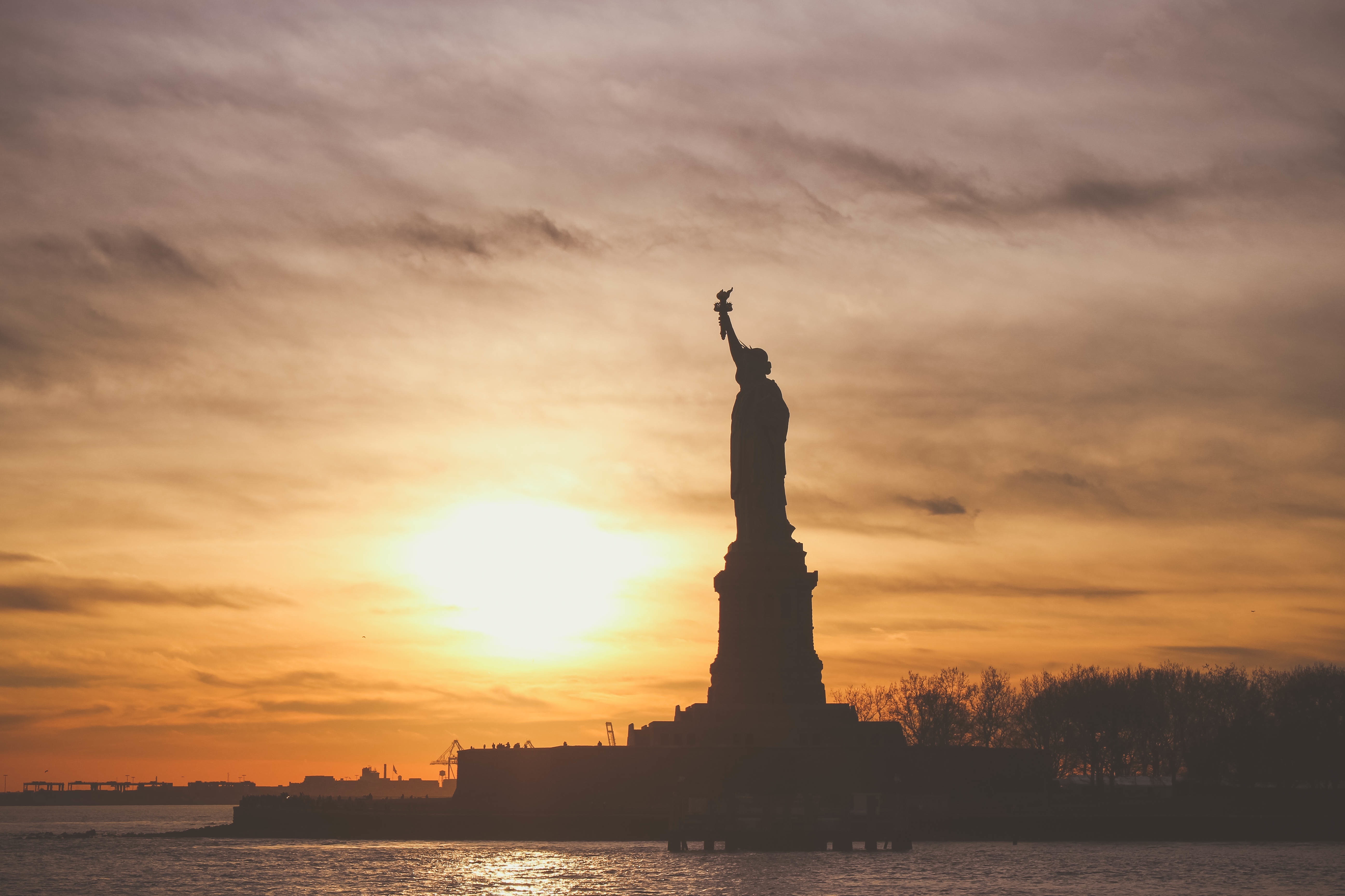 Download mobile wallpaper Sunset, Sky, Statue Of Liberty, Silhouette, Man Made for free.