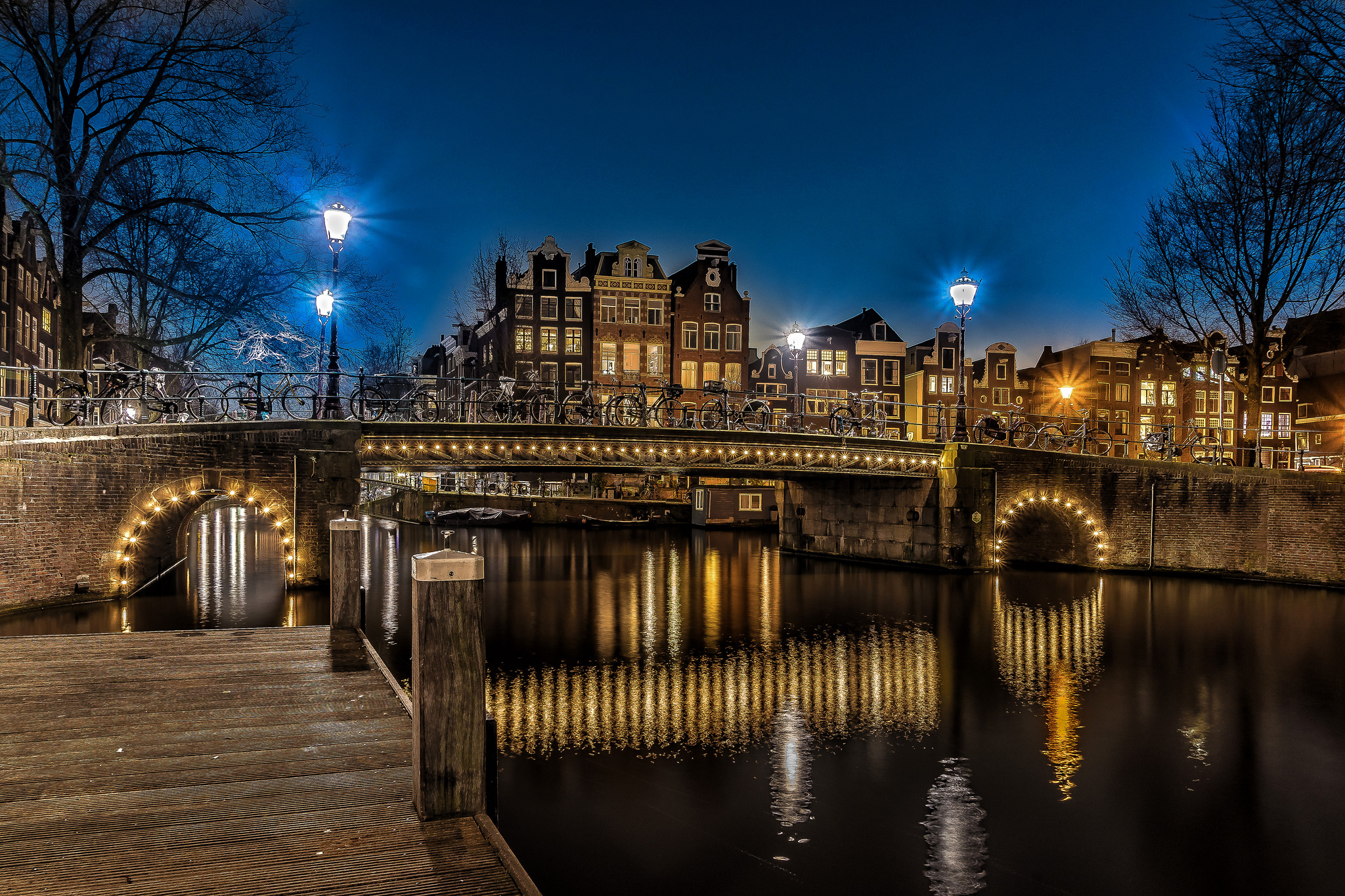 Free download wallpaper Cities, Night, Light, Bridge, Bicycle, Netherlands, Amsterdam, Man Made, Canal on your PC desktop
