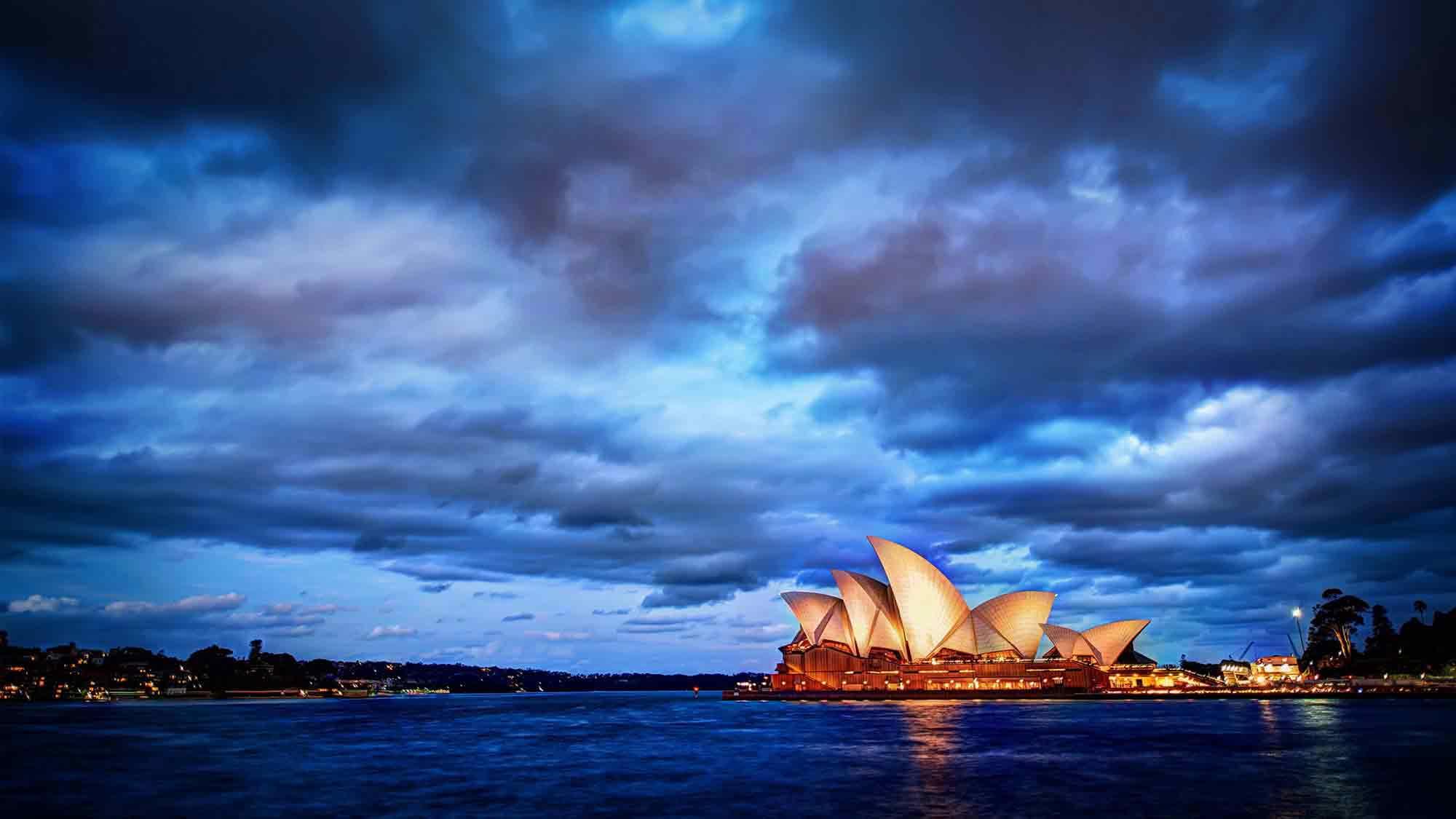 Скачать картинку Небо, Море, Океан, Сиднейский Оперный Театр, Сделано Человеком, Закат Солнца, Сидней Харбор в телефон бесплатно.