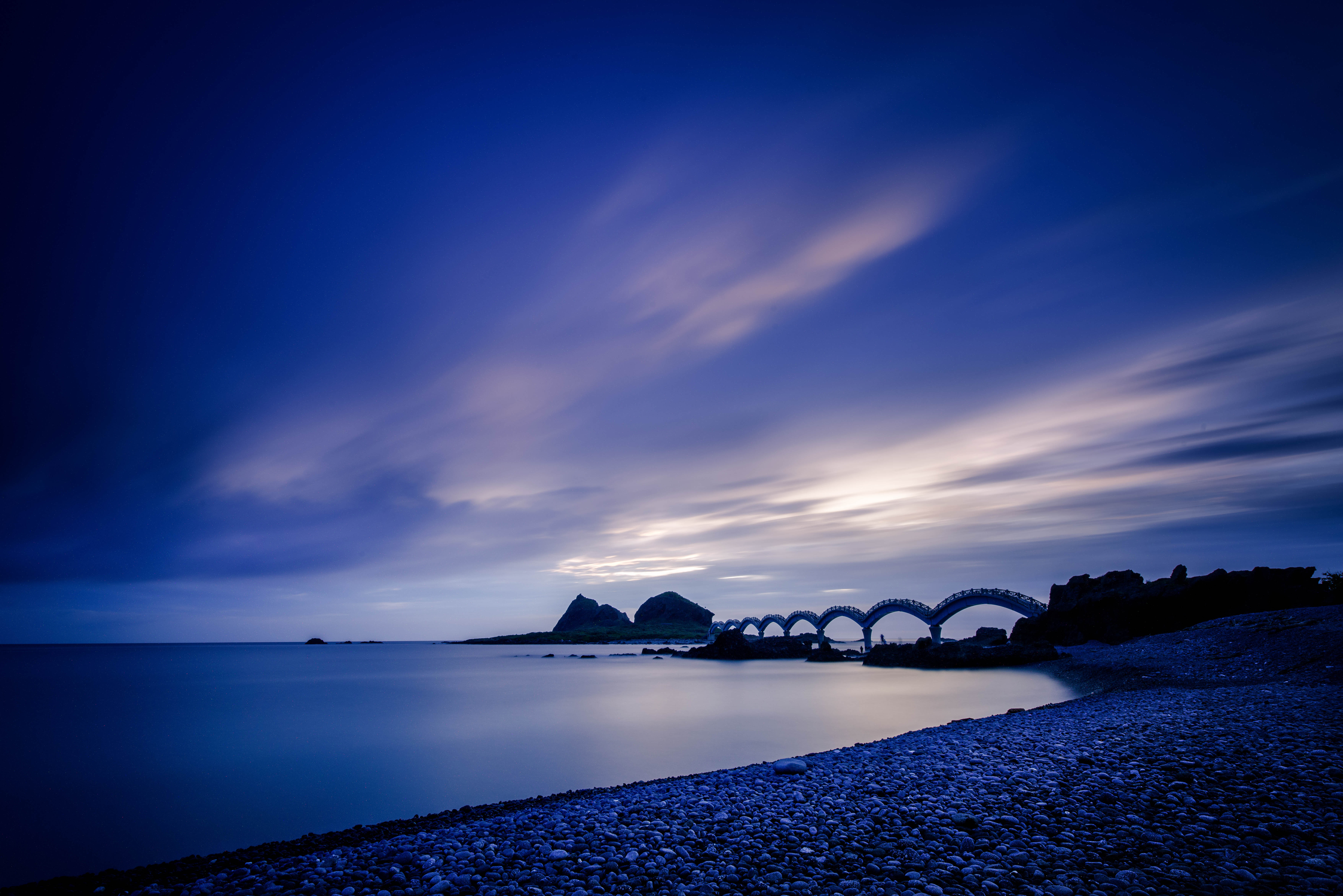 evening, nature, sunset, stones, sea, shore, bank, bridge phone wallpaper