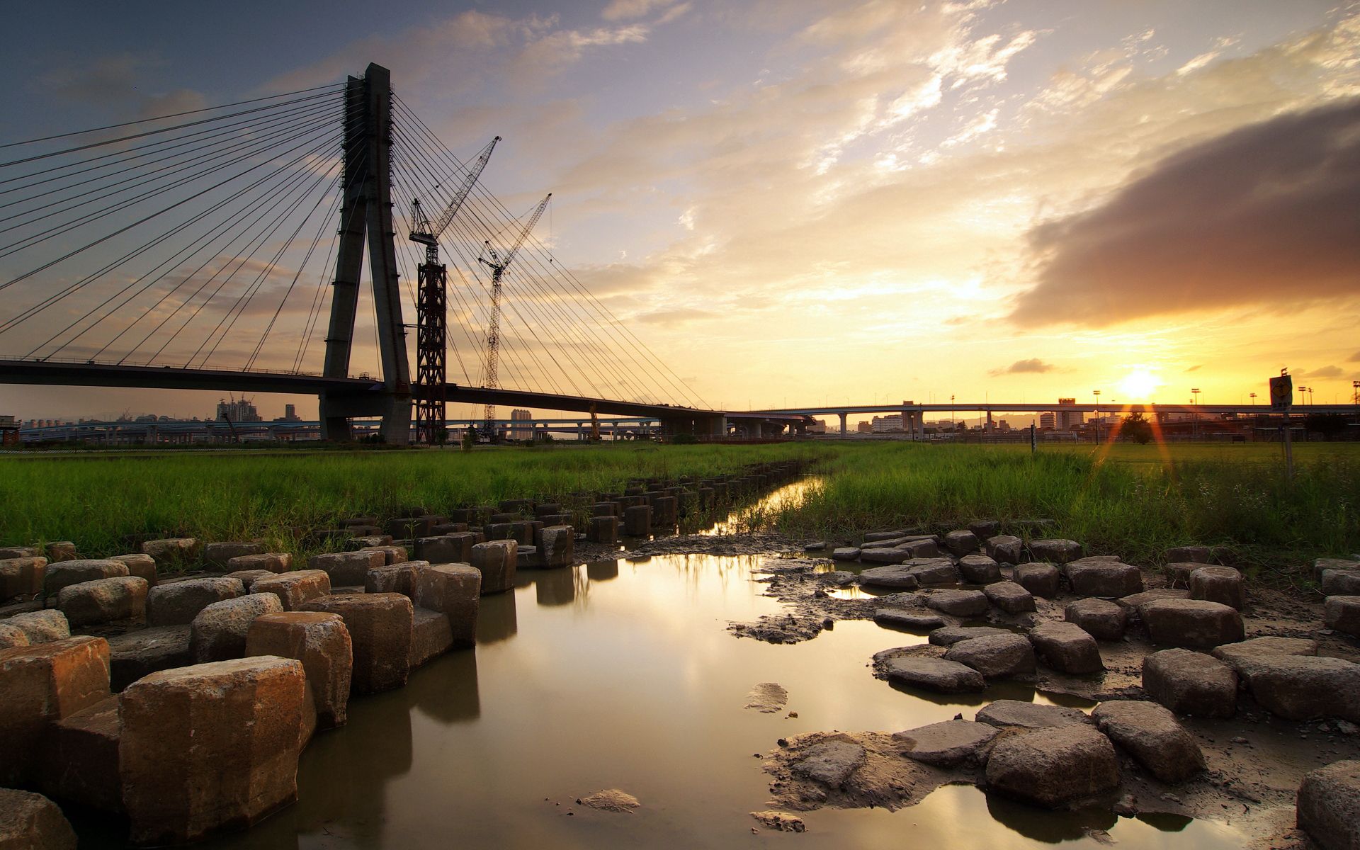 Download mobile wallpaper Cities, Sky, City, Building, Bridge, Evening, Rivers, Grass, Stones for free.