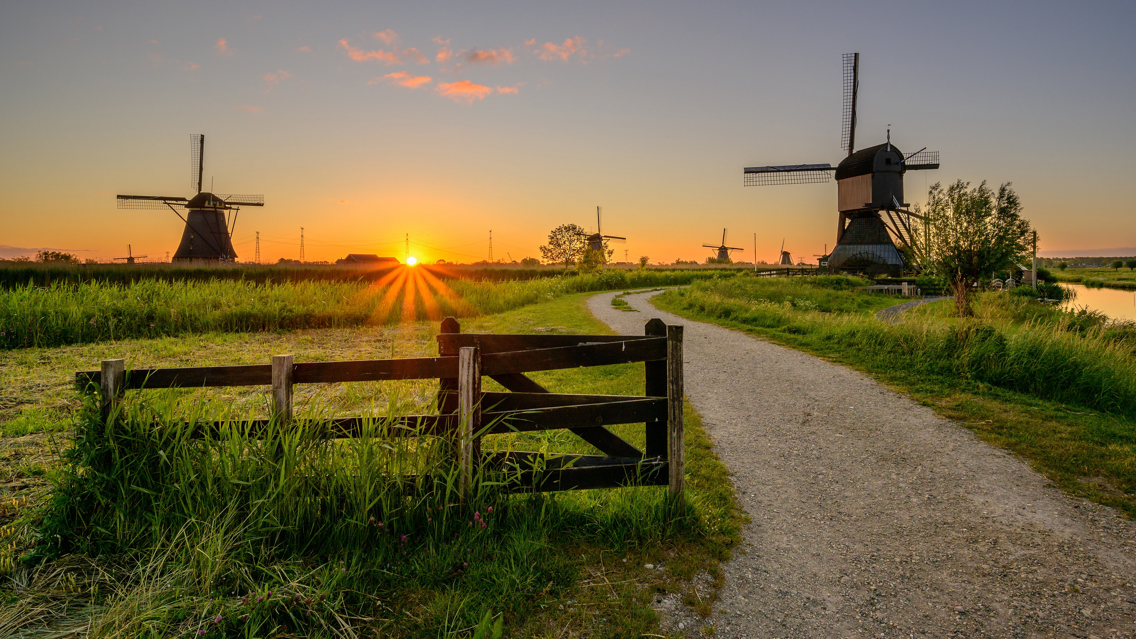 Download mobile wallpaper Sunset, Road, Field, Fence, Netherlands, Windmill, Man Made for free.