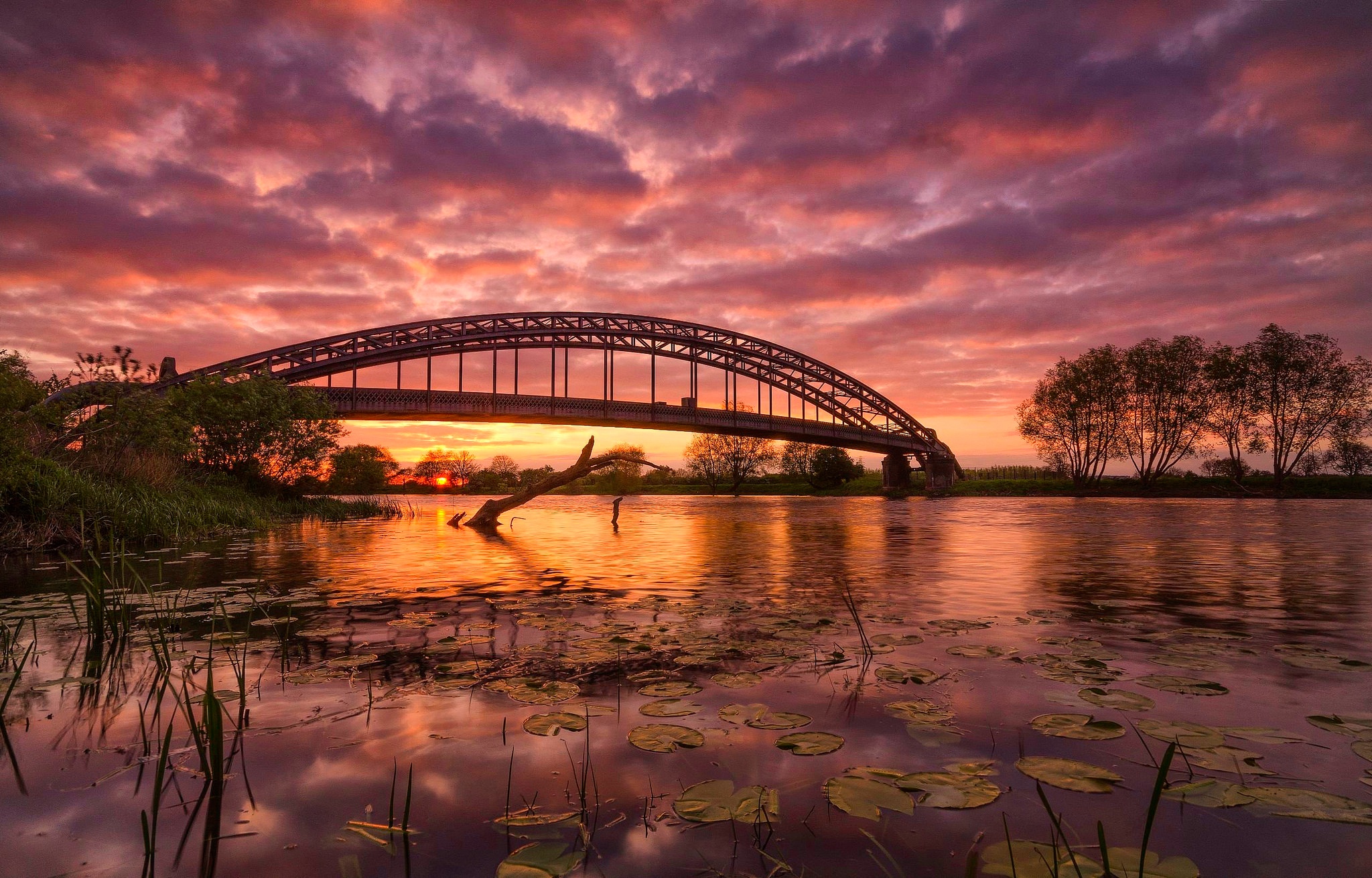 Download mobile wallpaper Nature, Bridges, Sunset, Sky, Bridge, Cloud, River, Man Made for free.