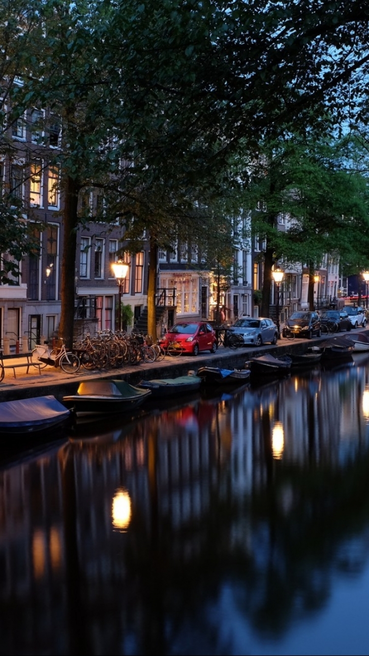 Скачать картинку Города, Река, Ночь, Город, Отражение, Свет, Нидерланды, Амстердам, Легкий, Сделано Человеком в телефон бесплатно.