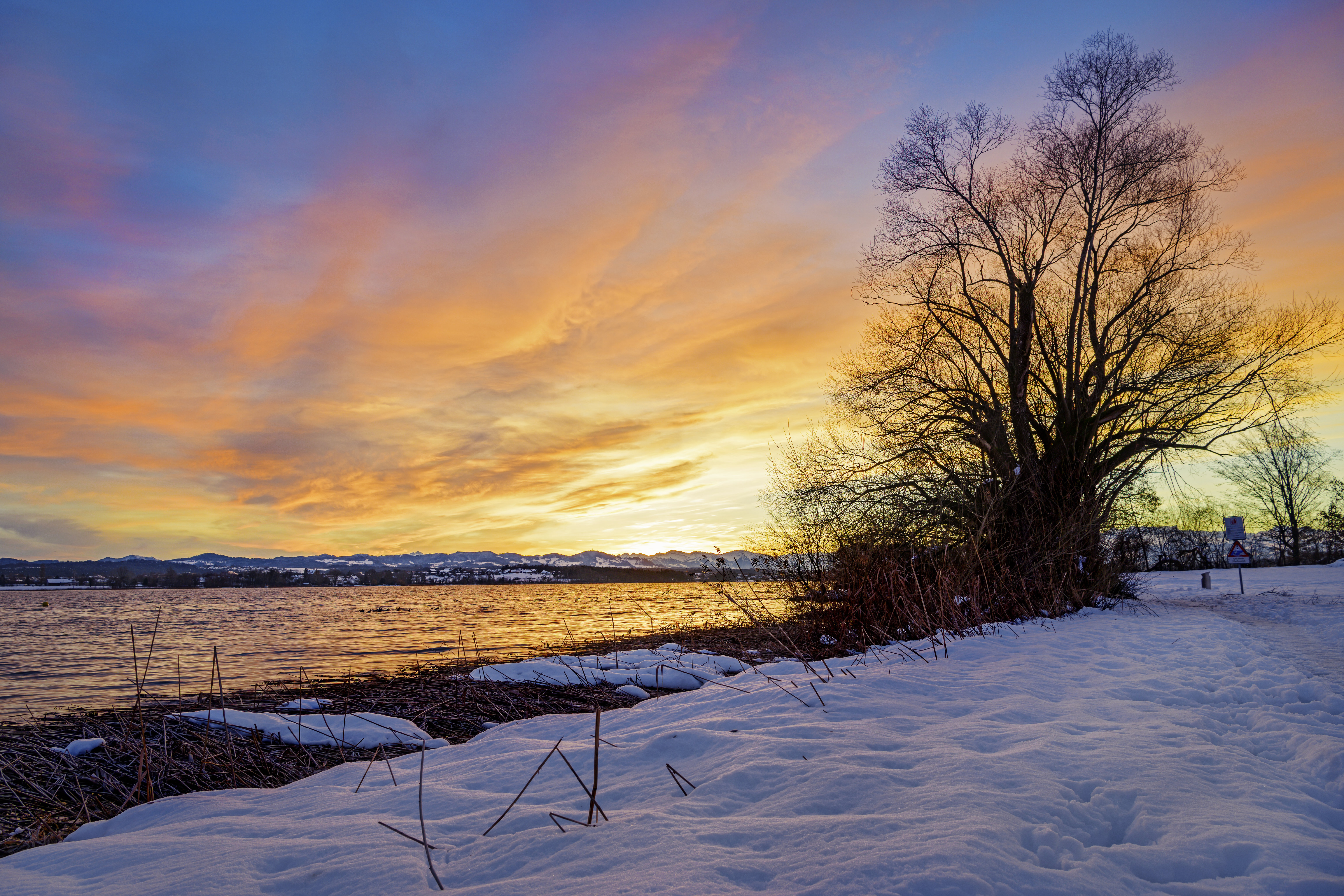 Download mobile wallpaper Snow, Winter, Wood, Sunset, Tree, Landscape, Nature, Lake for free.