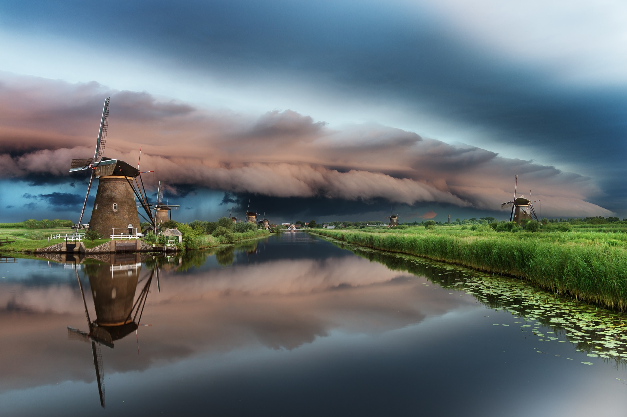 Download mobile wallpaper Sky, Reflection, Storm, Cloud, River, Windmill, Man Made for free.