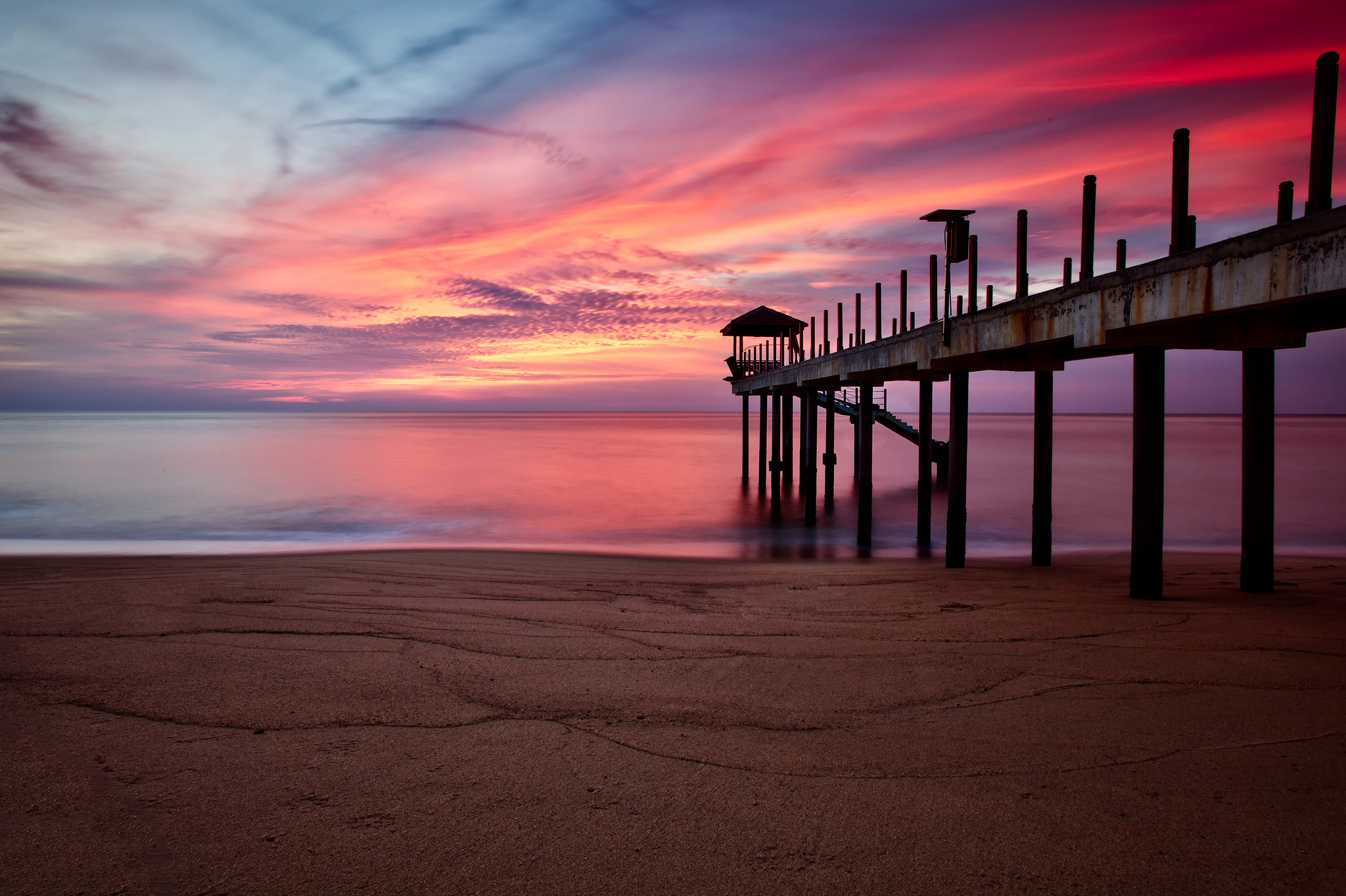 Download mobile wallpaper Sunset, Sky, Pink, Beach, Sand, Horizon, Pier, Ocean, Purple, Man Made for free.